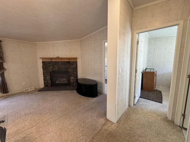 unfurnished living room with crown molding, light colored carpet, a fireplace, a textured ceiling, and visible vents