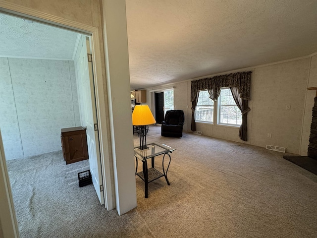 hallway with carpet floors, a textured ceiling, and visible vents