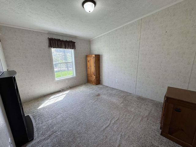 carpeted spare room featuring crown molding, a textured ceiling, and visible vents
