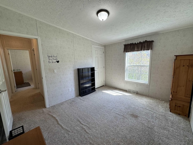 interior space with ornamental molding, a textured ceiling, and carpet flooring