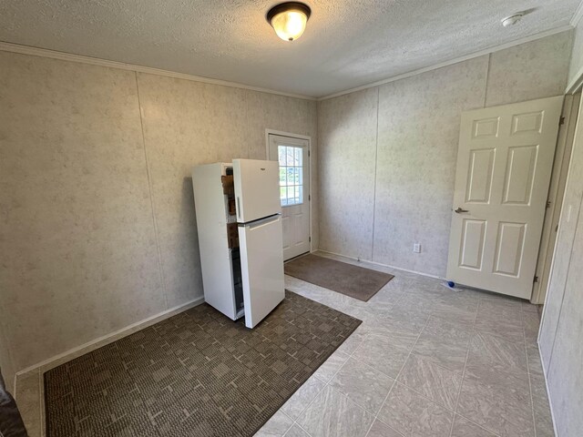 spare room featuring crown molding, a textured ceiling, and baseboards