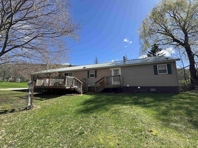 back of property featuring a wooden deck, a yard, and metal roof