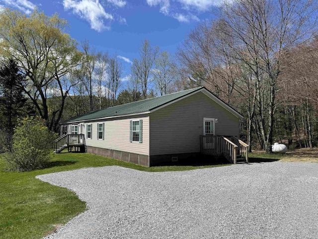 view of side of property with a lawn and metal roof