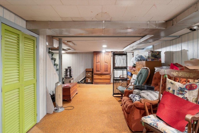 finished basement featuring wooden walls, carpet, and stairs