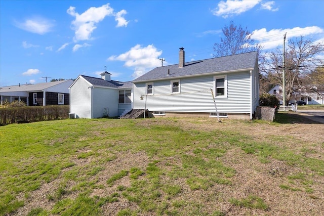 back of property with a chimney and a yard