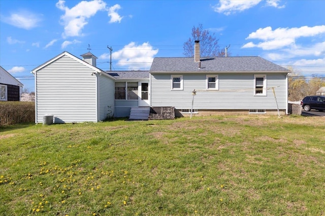 rear view of property featuring entry steps, a chimney, and a lawn