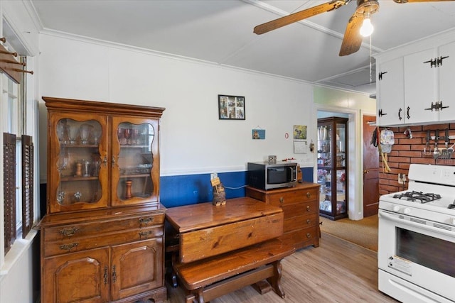kitchen with light wood-style floors, gas range gas stove, ceiling fan, stainless steel microwave, and white cabinets