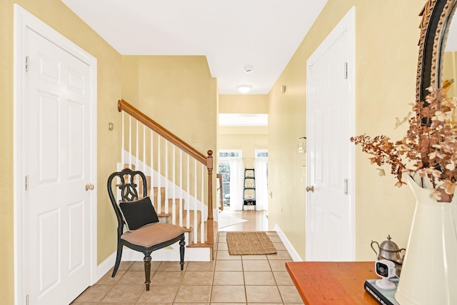 foyer with baseboards, stairs, and light tile patterned flooring