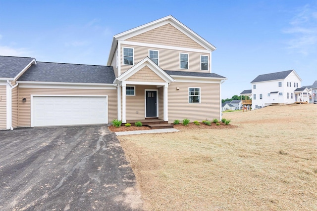 traditional home with roof with shingles, an attached garage, a front yard, and aphalt driveway