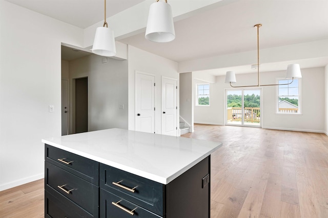 kitchen featuring dark cabinets, light countertops, baseboards, and light wood-style flooring