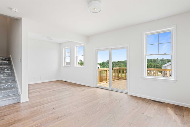 unfurnished living room with visible vents, baseboards, light wood finished floors, and stairs