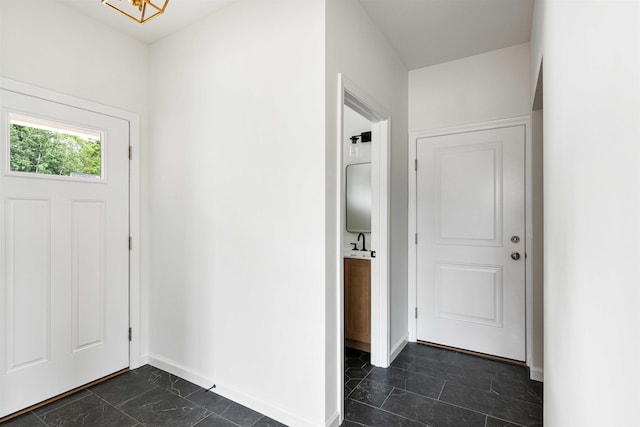 entryway with baseboards and a chandelier