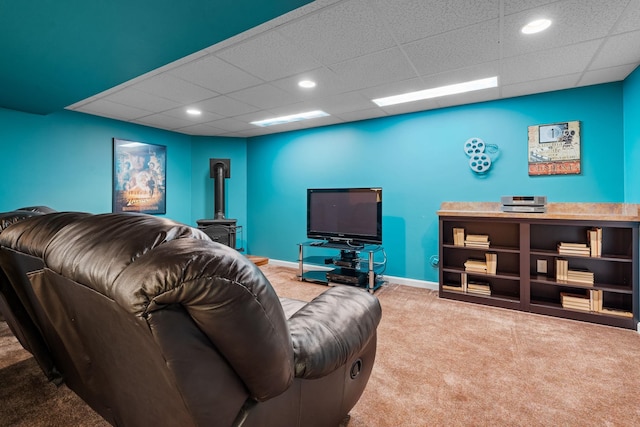 living area featuring a wood stove, baseboards, a drop ceiling, recessed lighting, and carpet