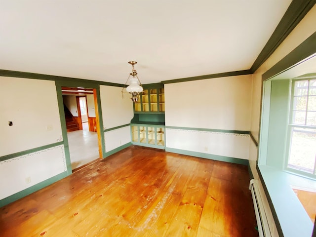 unfurnished room with crown molding, baseboards, a baseboard radiator, and hardwood / wood-style floors