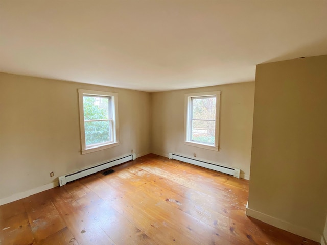 unfurnished room with light wood-type flooring, plenty of natural light, and a baseboard radiator