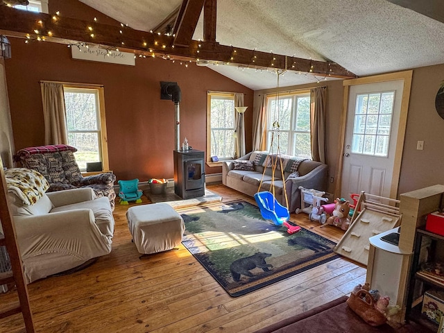 living area featuring a textured ceiling, hardwood / wood-style flooring, vaulted ceiling, and a wood stove