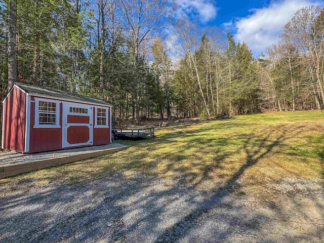 view of yard with a storage unit, an outdoor structure, and a wooded view