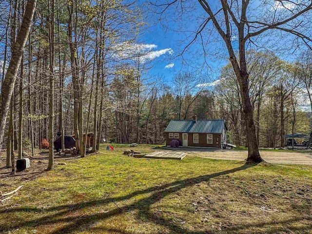 view of yard featuring a wooden deck, an outdoor structure, and a forest view