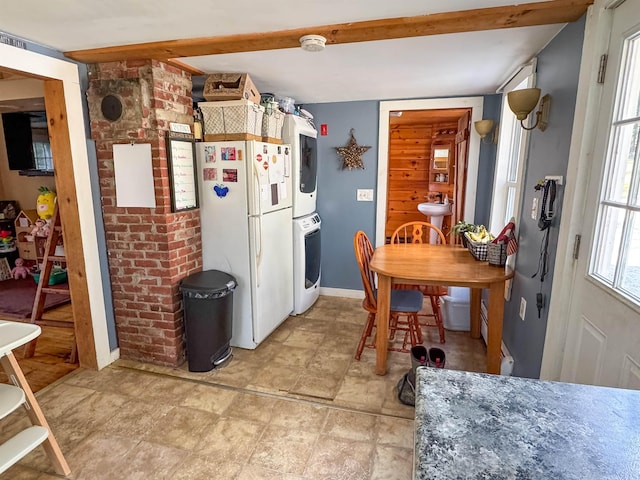 kitchen with freestanding refrigerator and stacked washer / dryer