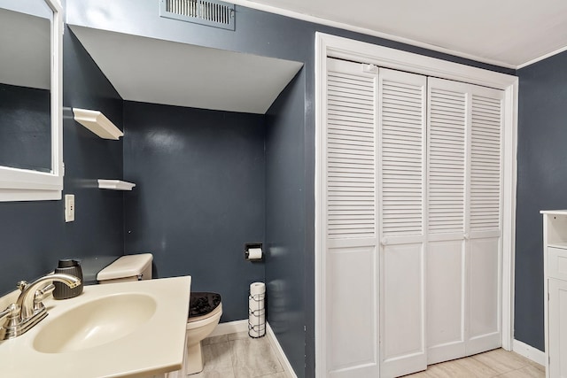 bathroom featuring visible vents, baseboards, toilet, and vanity