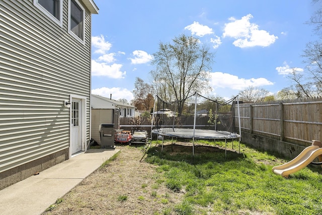 view of yard with a fenced backyard, a trampoline, and a playground