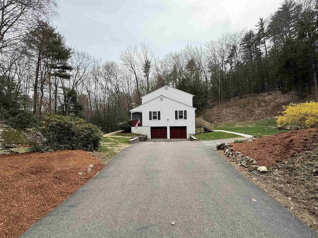 12 Nathaniel Dr, Amherst, NH 03031 - exterior space featuring stairs, an attached garage, driveway, and a wooded view