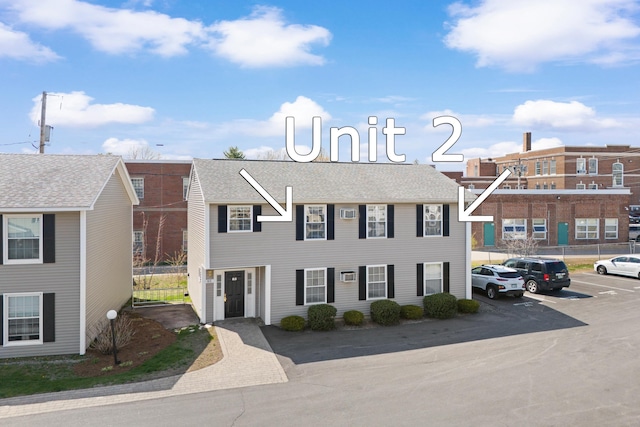 view of front of property featuring roof with shingles and uncovered parking