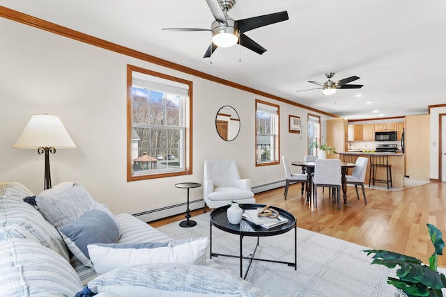 living room with a ceiling fan, crown molding, baseboard heating, baseboards, and light wood-style floors