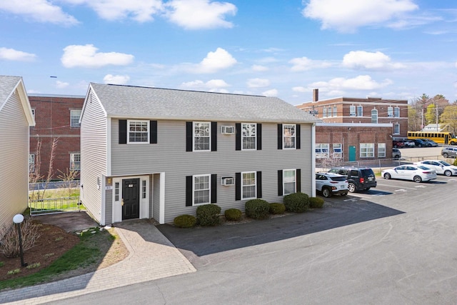 colonial house with a shingled roof and uncovered parking