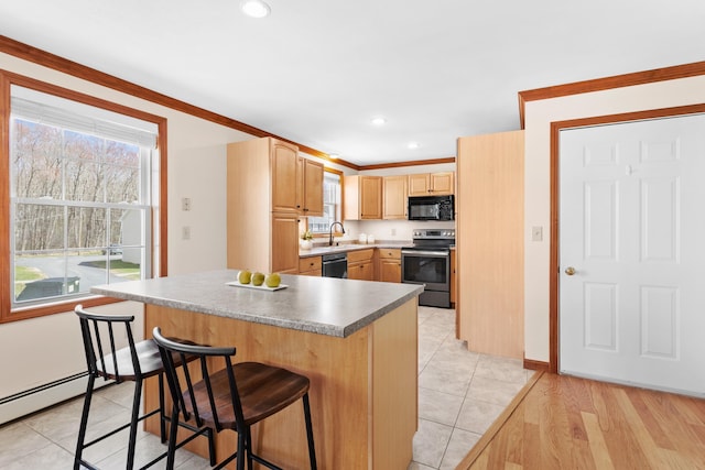 kitchen with black microwave, light brown cabinetry, stainless steel range with electric stovetop, a breakfast bar, and a wealth of natural light