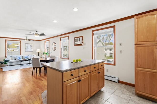 kitchen featuring a ceiling fan, crown molding, a center island, baseboards, and a baseboard radiator