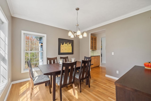 dining room with light wood-style floors, baseboards, crown molding, and a notable chandelier