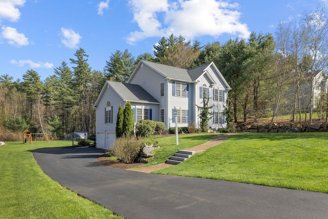 colonial inspired home with an attached garage, aphalt driveway, and a front yard