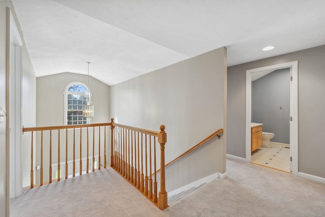 hall featuring a notable chandelier, light carpet, baseboards, an upstairs landing, and lofted ceiling