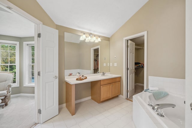 full bathroom with a walk in closet, a garden tub, vaulted ceiling, vanity, and a chandelier