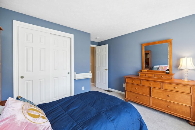 bedroom with a closet, baseboards, visible vents, and light carpet