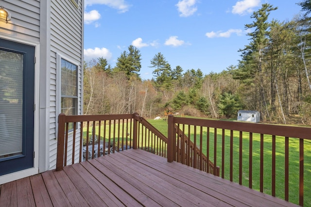 wooden deck featuring a lawn, an outbuilding, and a shed