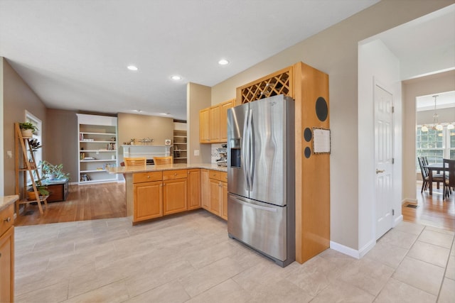 kitchen with stainless steel refrigerator with ice dispenser, light tile patterned floors, baseboards, a peninsula, and recessed lighting