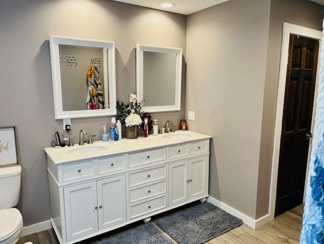 full bath with baseboards, a sink, wood finished floors, and toilet