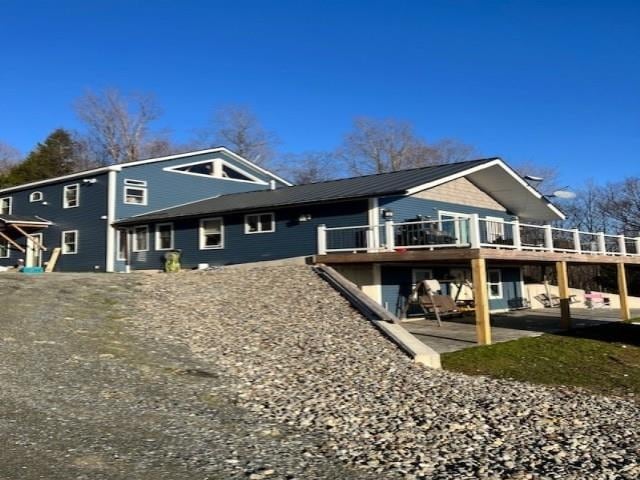 rear view of property with a patio area, a deck, and metal roof