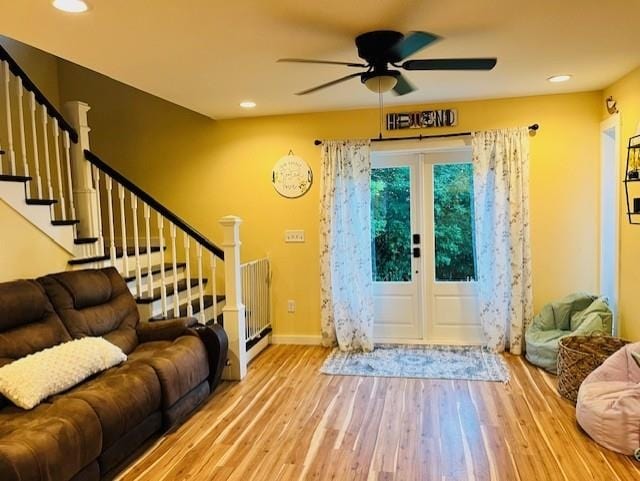 foyer entrance with a ceiling fan, baseboards, wood finished floors, and stairway
