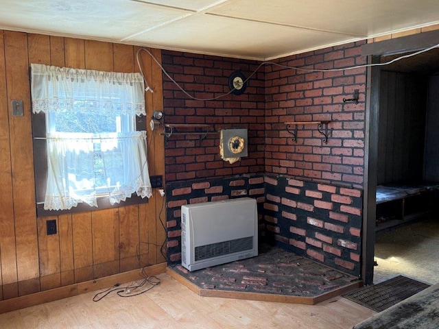 interior details with baseboards, heating unit, wood finished floors, and wooden walls