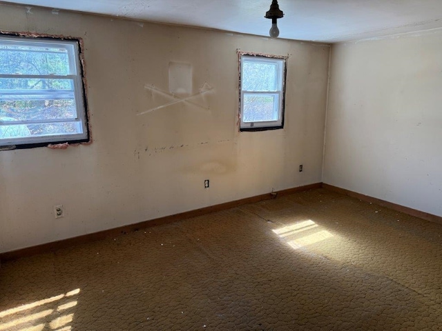 empty room featuring carpet flooring, baseboards, and a healthy amount of sunlight