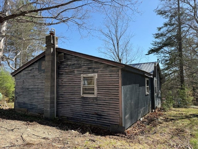 view of property exterior with a chimney and metal roof