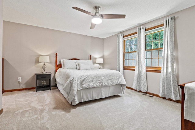 bedroom featuring carpet floors, visible vents, baseboards, ceiling fan, and a textured ceiling