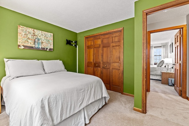 bedroom featuring carpet flooring, a textured ceiling, baseboards, and a closet