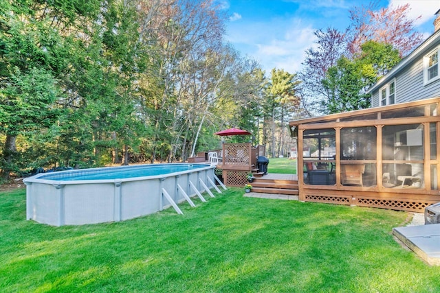 view of yard with a sunroom, an outdoor pool, and a deck