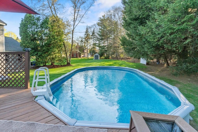 pool with a lawn, a wooden deck, an outdoor structure, and a storage unit