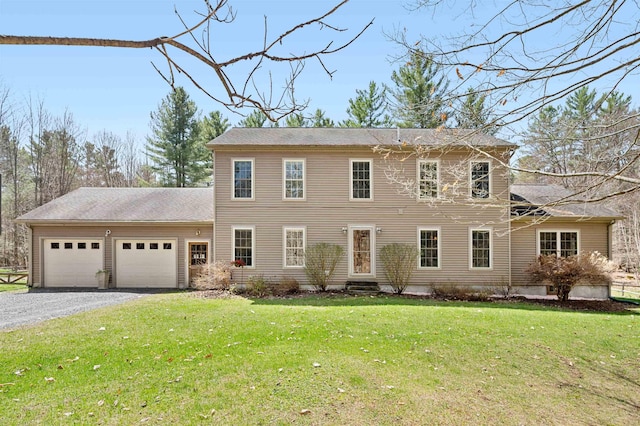 colonial house featuring a garage, a front lawn, and gravel driveway