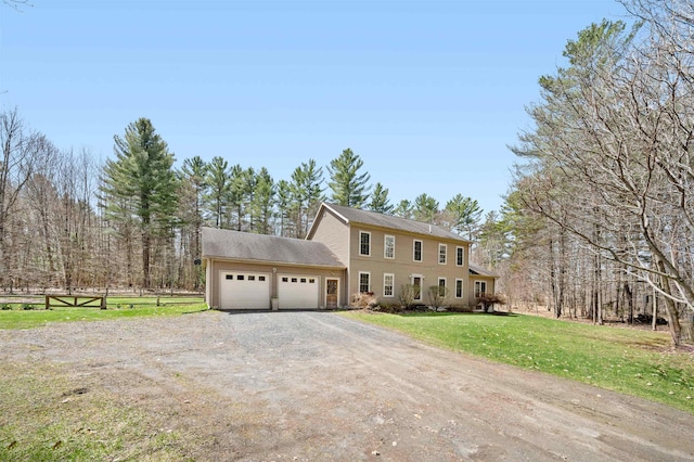 colonial home featuring an attached garage, fence, driveway, and a front yard